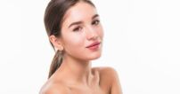Portrait of beautiful woman with perfect face on white background Retrato frontal de una mujer joven de piel luminosa sobre fondo blanco, imagen de recurso para tratamientos de belleza facial